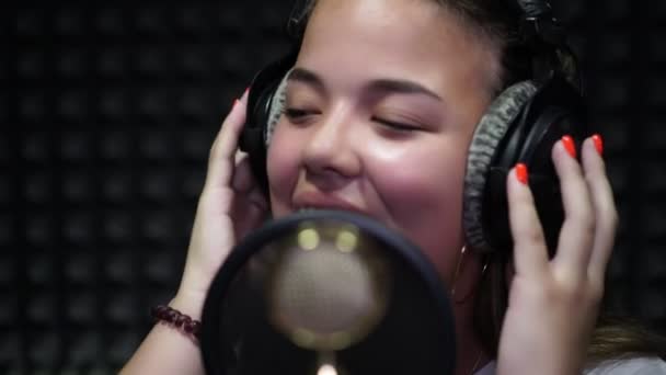 Estudio de grabación vocal. Retrato de una chica que canta en un micrófono . — Vídeo de stock