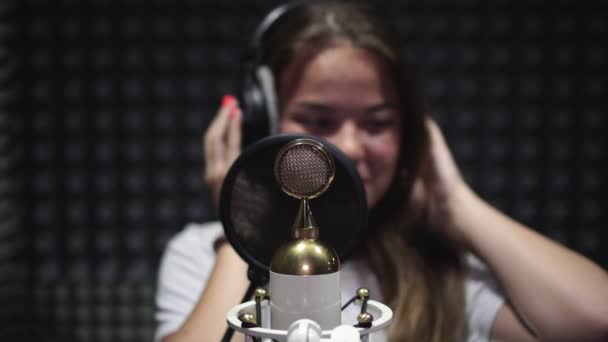 Estúdio de gravação vocal. Jovem cantora cantando em um microfone . — Vídeo de Stock