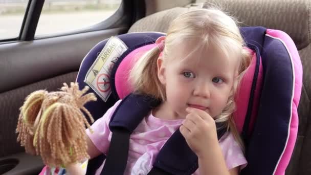 Bebé niña cabalga en el coche en un asiento de coche para niños . — Vídeos de Stock