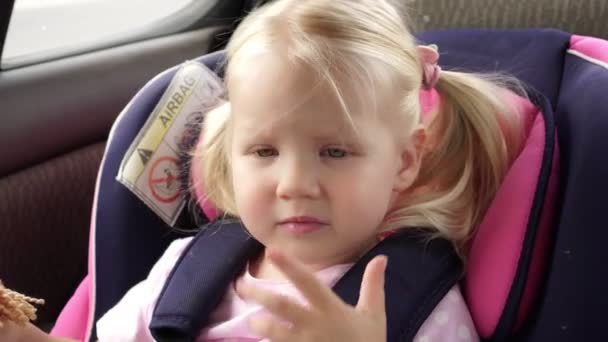 Маленька дівчинка їде в машині на дитячому автокріслі . — стокове відео