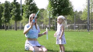 Kadın ve çocuk parkta sabun kabarcıkları ile oynamak.