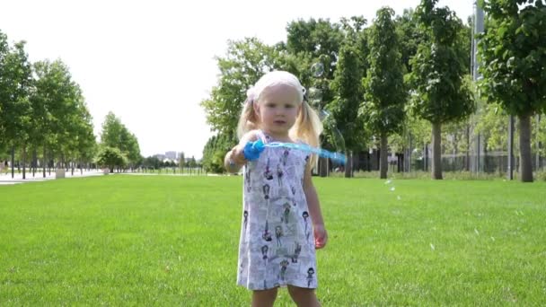Fröhliches Kindermädchen pustet Seifenblasen im Sommerpark. — Stockvideo