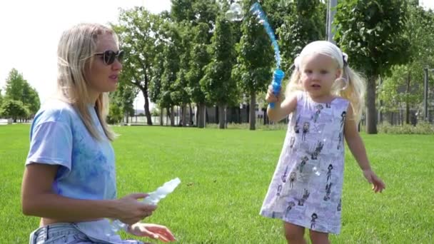 Máma s dcerou hrají v parku mýdlové bubliny. — Stock video