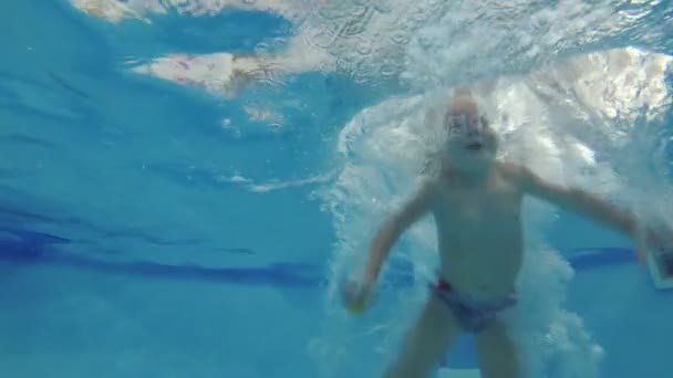 Dziecko dziewczyna nurkuje i płodzi w basenie pod wodą. — Wideo stockowe