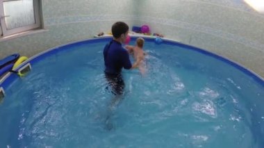 öğretmen havuzda yüzmek için küçük bir çocuk öğretir.