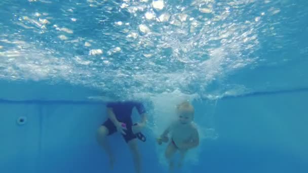 Un instructor de natación enseña a un niño pequeño a nadar en una piscina . — Vídeos de Stock