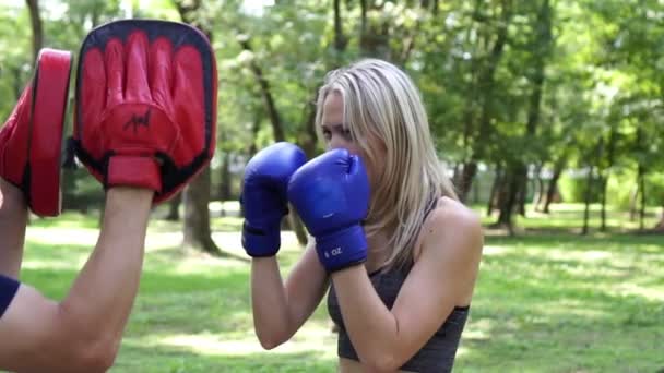 A jovem está envolvida no boxe com um treinador. Treinamento de boxe, câmera lenta . — Vídeo de Stock