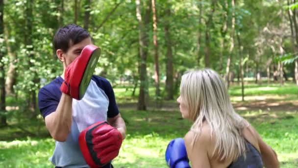 Женщина с тренером учится боксу, замедленной съемке. Женский бокс в парке . — стоковое видео