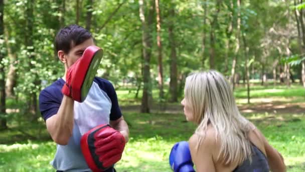 Uma mulher com um treinador está aprendendo boxe, câmera lenta. Mulher boxe no parque . — Vídeo de Stock