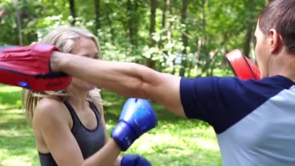 Uma mulher está a lutar com um treinador. Treinamento de boxe, mulher moderna . — Vídeo de Stock