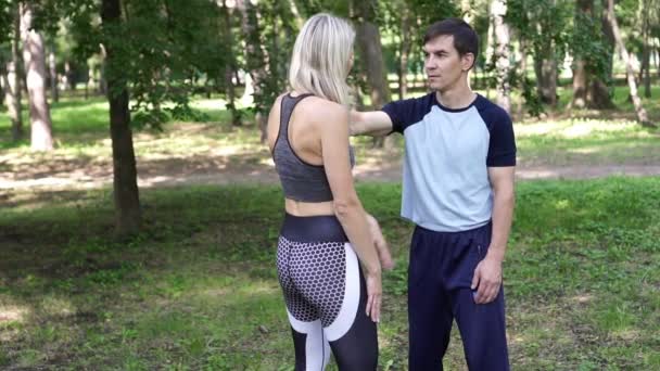 Mladá žena se zabývá sporty v bojových uměních v parku. — Stock video