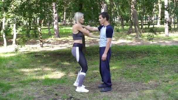 Homem e a mulher estão envolvidos em artes marciais no parque . — Vídeo de Stock