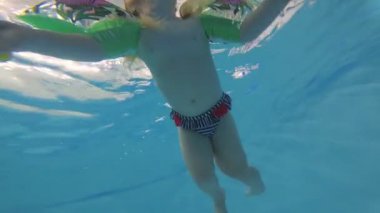 çocuk yüzmek için manşetlerle havuzda yüzer. Sualtı çekim.