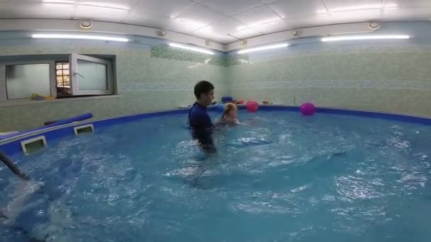 Instruktor učí dítě plavat v bazénu. — Stock video