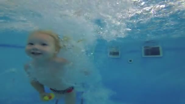 Malé dítě se potápí a plaví pod vodou v bazénu. Zpomaleně. — Stock video