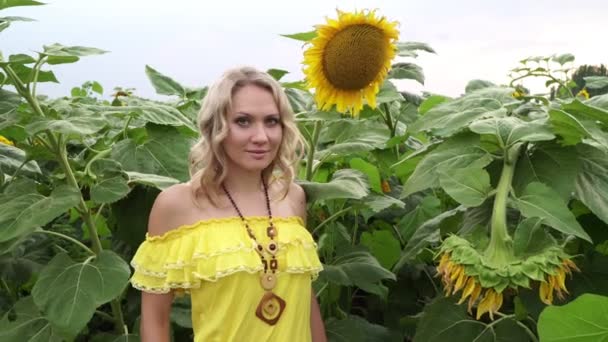 Portret van een jonge vrouw op een achtergrond van zonnebloemen. — Stockvideo