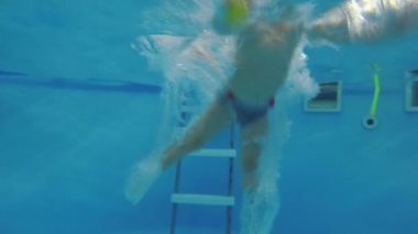 Küçük bir çocuk dalış ve çocuk havuzunda yüzer.