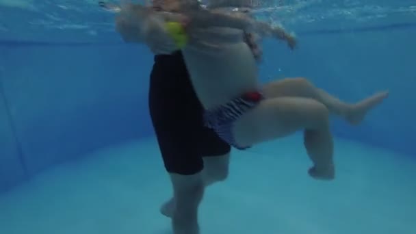 Küçük bir çocuk çocuk havuzunda bir koç ile yüzmeyi öğrenir. — Stok video