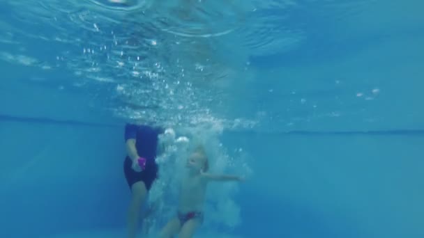 Een klein kind duikt onder het water in het kinderbad. — Stockvideo