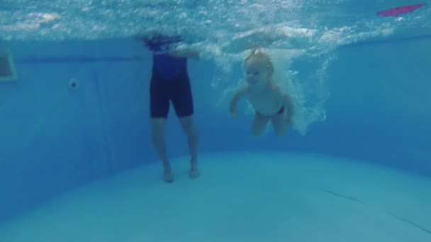小さな子供がスイミングプールで水中を泳ぐ — ストック動画