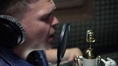 Bir erkek şarkıcı rap okur, bir kayıt stüdyosunda şarkı kaydeder..