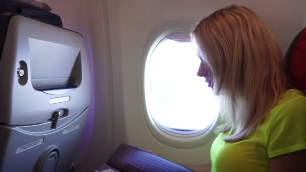 Пассажирка летит в самолете и читает журнал . — стоковое видео