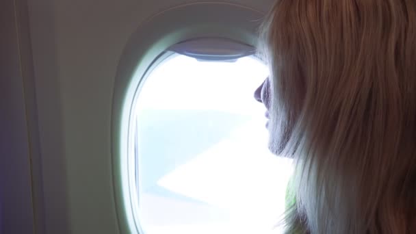 En kvinna flyger i ett flygplan och tittar ut genom fönstret.. — Stockvideo
