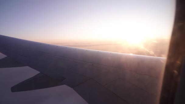Vleugel van een vliegtuig tegen zonsondergang of zonsopgang, zicht vanuit het raam. — Stockvideo