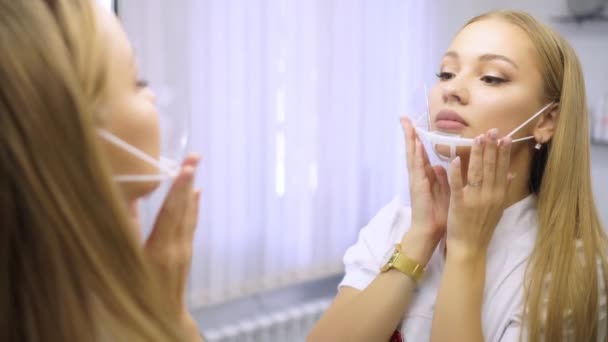 Jovem médico bonito fêmea coloca uma máscara na frente de um espelho . — Vídeo de Stock