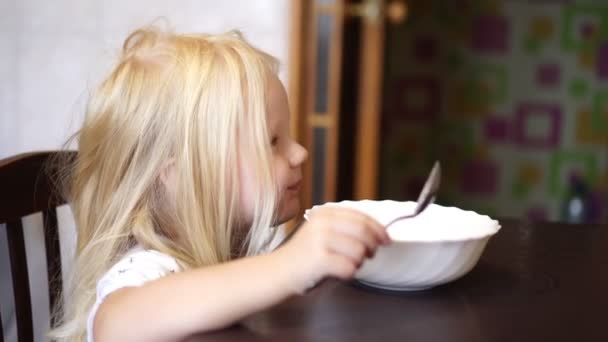 Mädchen frühstückt am Tisch. kleines Mädchen isst in der Küche. — Stockvideo