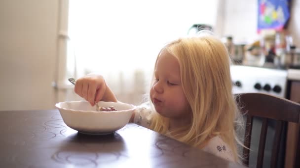 Kleines Mädchen frühstückt in der Küche. Mädchen isst am Tisch. — Stockvideo
