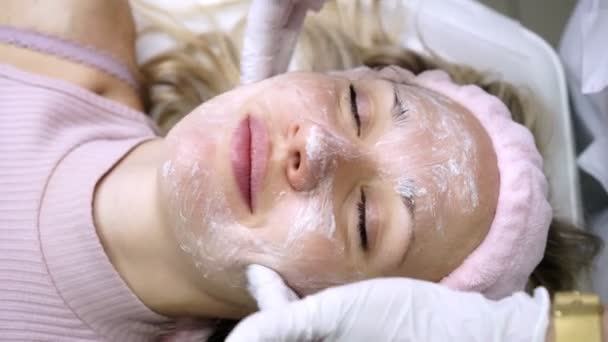 Estetista mette crema sul viso di una donna in un salone di bellezza . — Video Stock