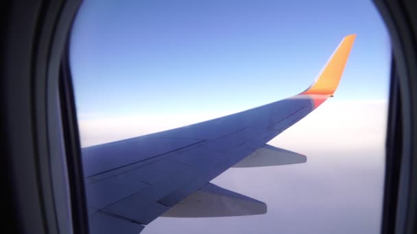 Ala de un avión de pasajeros contra un cielo azul. Vista desde la ventana del avión . — Vídeos de Stock