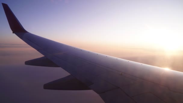 Vliegtuig vleugel op een achtergrond van zonsopgang of zonsondergang, de stralen van de zon en wolken. — Stockvideo