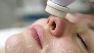 Genç bir kadın güzellik salonunda soyunuyor. Bir güzellik uzmanı tarafından yüz temizleme sırasında kadın.