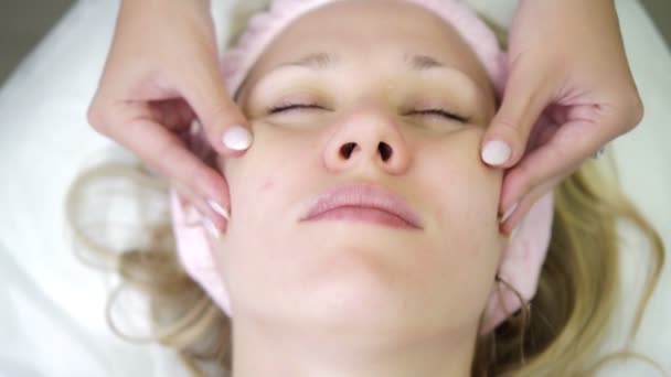 Jovem em um salão de beleza, massagem facial na pele, cosmetologia . — Vídeo de Stock