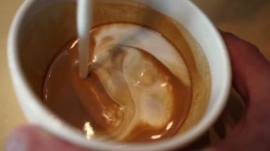 Baristo cappuccino doldurur ve yakın plan sütle bir kalp çizer..