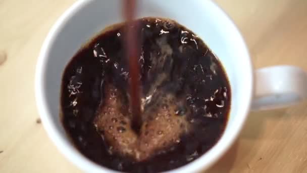 Americano café noir est versé dans une tasse blanche, gros plan .