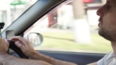 Bir adam araba kullanıyor ve navigatörü akıllı telefonda kullanıyor.
