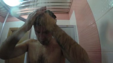 Genç adam duşta yıkanır, ağır çekimde..