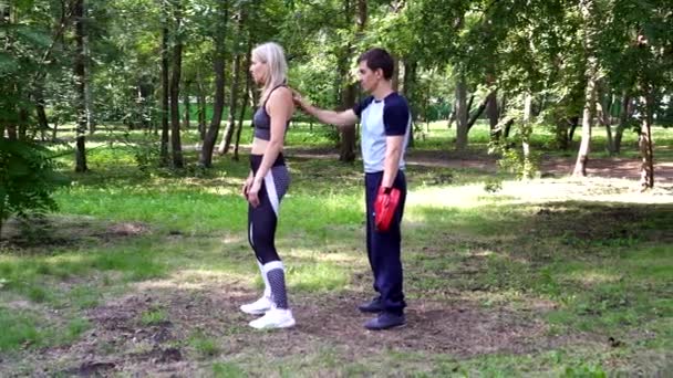 En kvinna med en tränare är engagerad i kampsport i parken. — Stockvideo