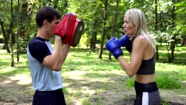 Hermosa mujer está boxeando en el parque con un entrenador . — Vídeos de Stock