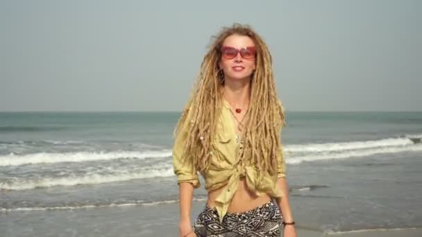 En ung hippiekvinna dansar på stranden. Hipster flicka med dreadlocks — Stockvideo