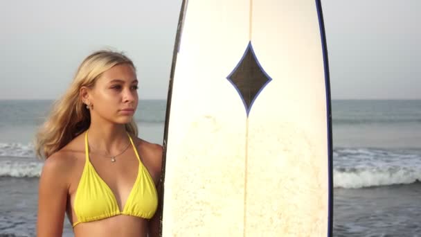 サーフボードと海の背景に美しいサーファーの女の子の肖像画 — ストック動画