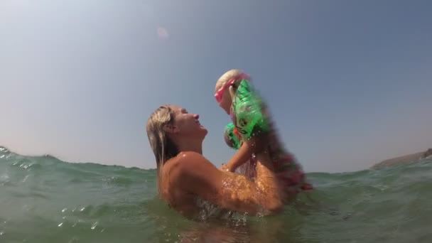 Mama wirft das Baby ins Meer. Die Familie spielt und schwimmt im Meer — Stockvideo