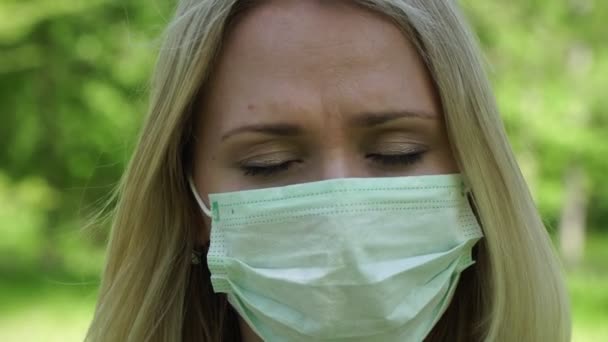 Droevige, verdrietige jonge vrouw met een medisch masker. Droevig meisje met een beschermend masker — Stockvideo