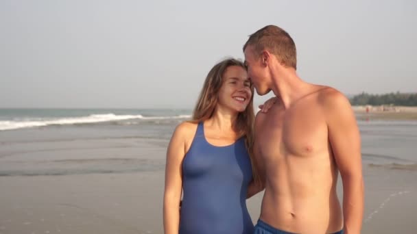 Una joven pareja enamorada pasea por una playa de arena. Familia de recién casados en el mar — Vídeos de Stock