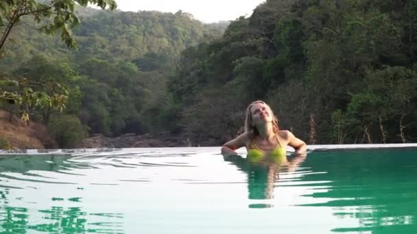 Μια νεαρή γυναίκα χαλαρώνει και απολαμβάνει σε μια υπαίθρια πισίνα — Αρχείο Βίντεο