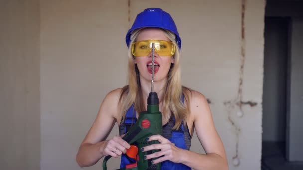 Fiatal szexi nő építész vagy munkás izgatottan nyalogatja a fúrót. Szexi lány építő — Stock videók