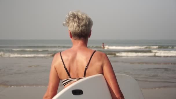 Emekli insanlar aktif ve sağlıklı bir yaşam tarzı ve spor yapıyorlar. Büyükanne sörf yapıyor. — Stok video